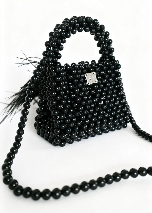 Black beaded handbag with tassel on a white background